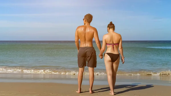 Bonita pareja joven caminar a lo largo de la playa al agua del océano — Foto de Stock