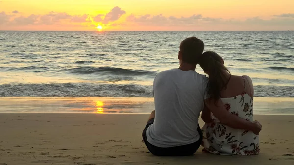 Encantador jovem casal abraços e beijos sentados na praia do oceano — Fotografia de Stock