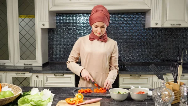 Mujer en hijab se para en cocina mesa de corte de verduras — Foto de Stock
