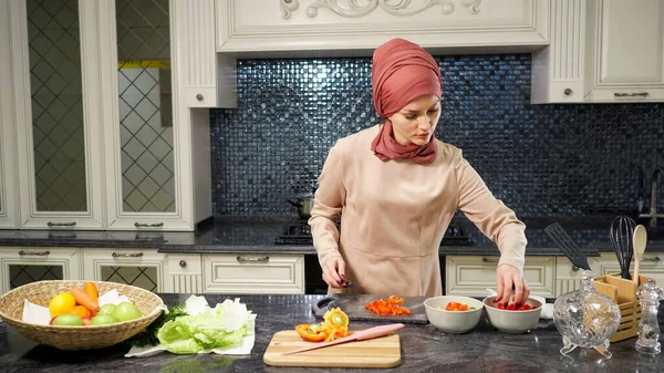 Mujer en hijab se para en cocina mesa de corte de verduras —  Fotos de Stock