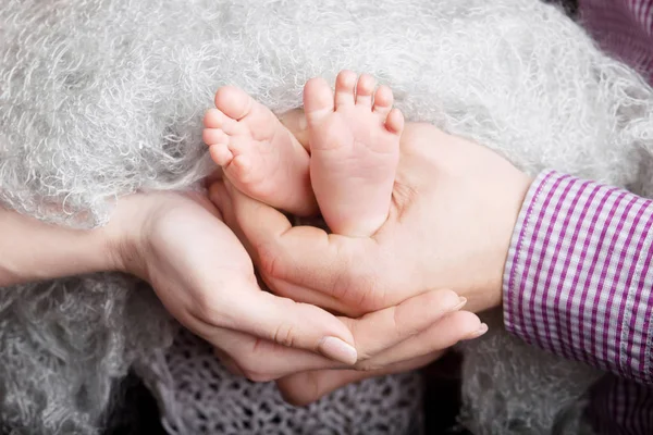 両親の手で赤ちゃんの足。親に小さな新生児の足 — ストック写真