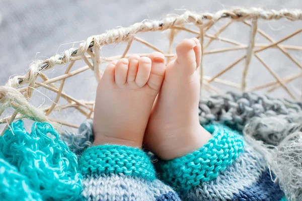 Крупный план новорожденных ног в вязаной клетке — стоковое фото