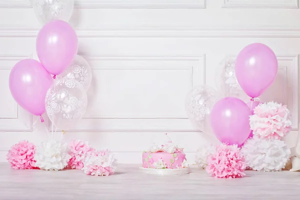 Festlig tårta, pomponger och ballonger. Vit och rosa färg. Födels — Stockfoto