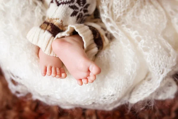 Крупный план новорожденных ног в вязаной клетке — стоковое фото