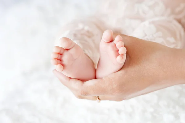 Pieds de bébé entre les mains de la mère. Maman et son enfant . — Photo