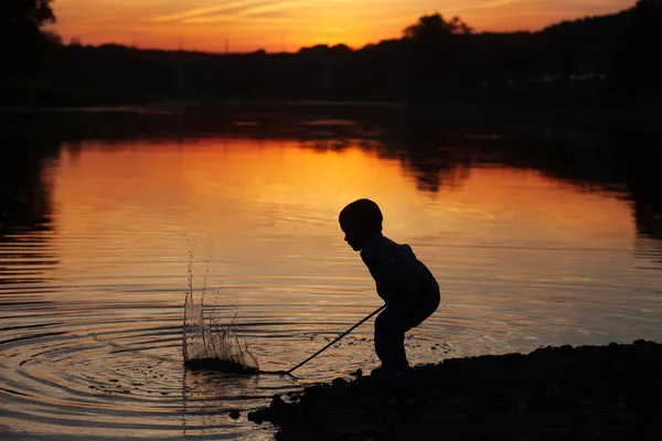 Dítě hraje ve vodě při západu slunce — Stock fotografie