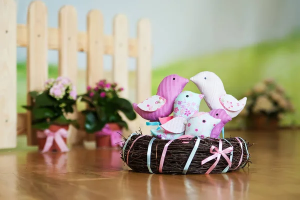 Lente decoratieve vogels in een nest op een houten vloer. Pasen deco — Stockfoto