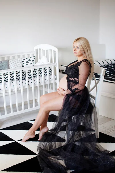 Krásná těhotná žena sedí v černé a bílé domácím místnosti — Stock fotografie