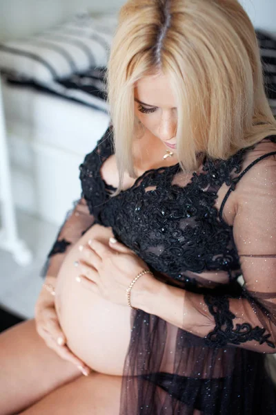 Hermosa mujer embarazada se sienta en la habitación del hogar en blanco y negro — Foto de Stock