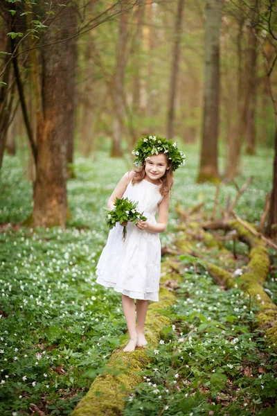 Красива маленька дівчинка в білій сукні ходить у весняному лісі — стокове фото