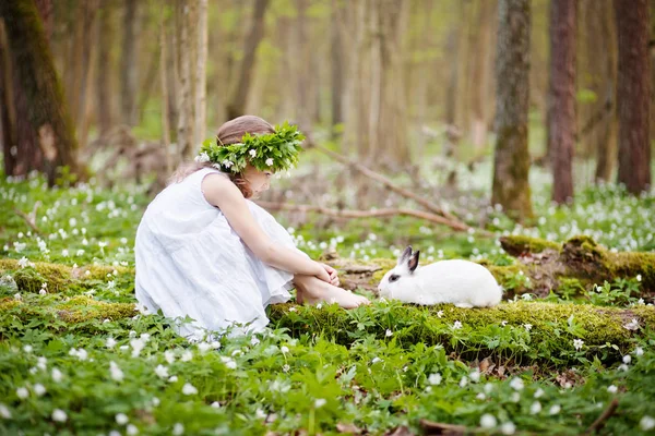 Schöne kleine Mädchen in einem weißen Kleid Flechten mit weißem Kaninchen — Stockfoto