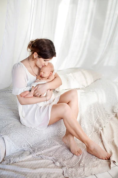 Ευτυχισμένη οικογένεια μητέρα παίζει και αγκαλιά με το νεογέννητο μωρό στο κρεβάτι — Φωτογραφία Αρχείου