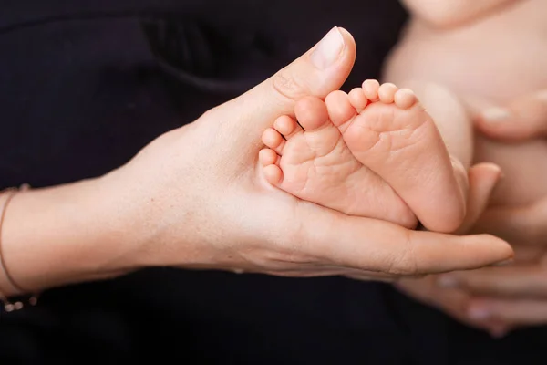 Boldog család koncepció. Újszülött baba láb anya kezében fekete — Stock Fotó
