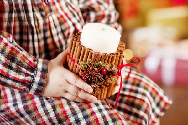 Burning candle in the hands of a girl. Christmas candle. Christmas decor. Woman\'s hands holding beautiful candle with fire. Copy space