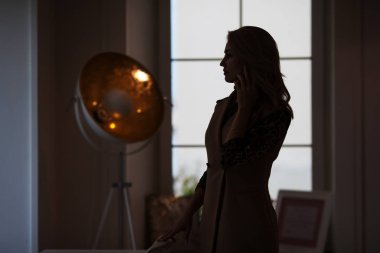 Telefonda konuşan düşünceli genç bir bayan. Bir kadının silueti.