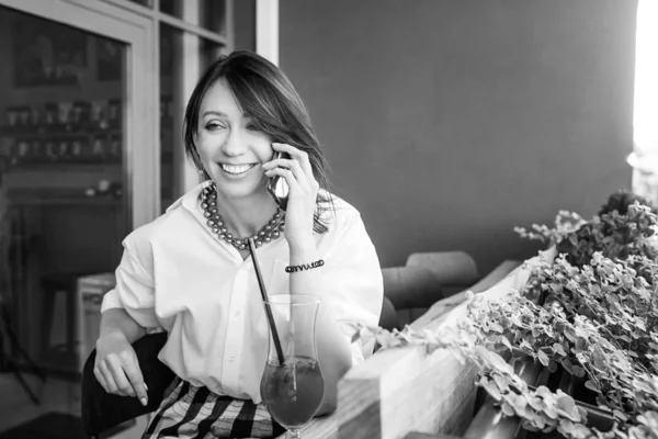 Улыбающаяся очаровательная женщина звонит с мобильного телефона во время сидения — стоковое фото