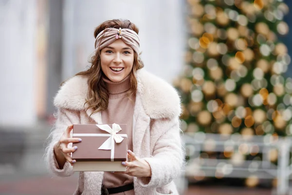 Jovem feliz segurando um presente em um mercado de Natal. Tempo para — Fotografia de Stock