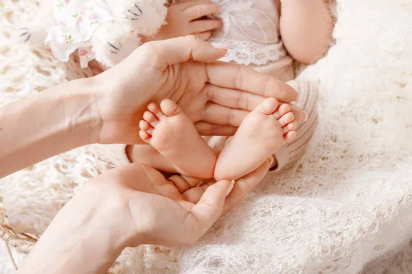Детские лапки в руках матери. Tiny Newborn Baby 's feet on female Sh — стоковое фото