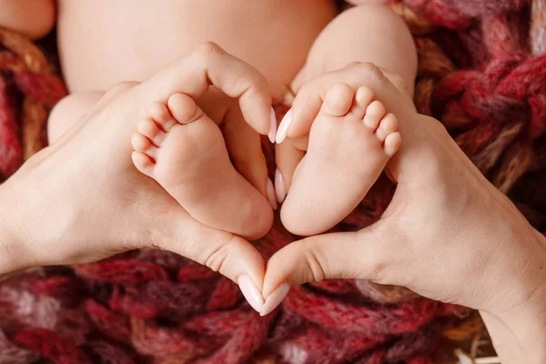 Baby feet in mother hands - hearth shape closeup. Mom and her Ch — Stockfoto