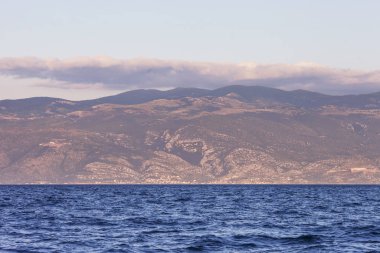Gün batımında ya da gün doğumunda deniz ve dağların manzarası. Büyüklük 