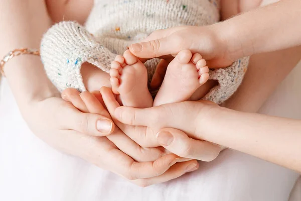 Barn fötter i mor och bror händer. Små nyfödda barnets fötter — Stockfoto