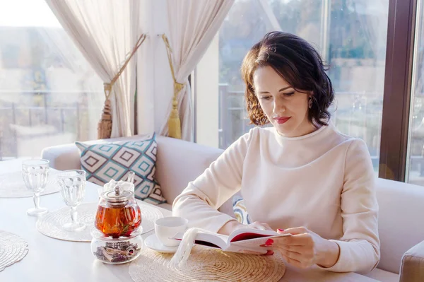 女性は窓の近くのカフェで本を読んで — ストック写真