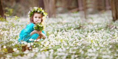 Mavi elbiseli güzel bir kız bahar ormanında yürüyor. Kafasında çiçeklerden çelenk olan güzel bir kızın portresi. Paskalya zamanı. Tatlı bahçıvan, kar ekiyor. Uzayı metin için kopyala. Pankart