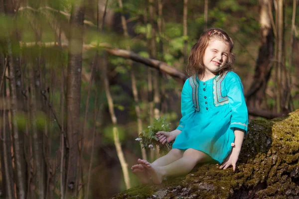 春の森の中を歩く青いドレスの美しい少女 下落ダウン ツリー上に座っているきれいな女の子 夏に野外で遊ぶ子供 イースターの時期 — ストック写真
