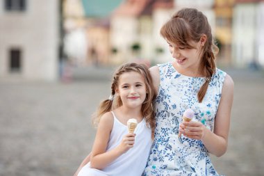 Kız kardeşler birlikte vakit geçirirken dondurma yiyorlar. Küçük güzel kızlar şehirde eğleniyor.