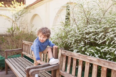 Baharda parkta oynayıp koşan mutlu çocuk. Küçük gülümseyen çocuk şehir parkında oynuyor.