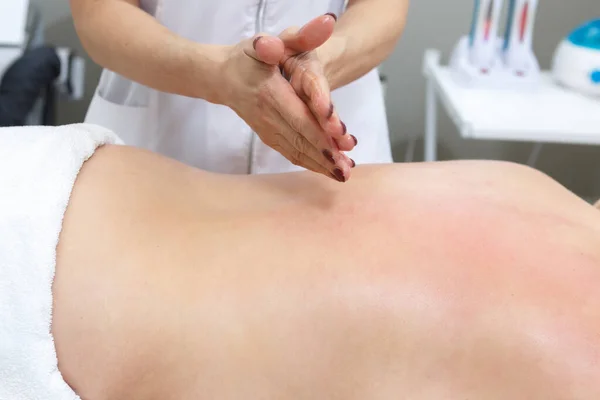 Cosmetologist gives a back massage to a woman in a beauty salon