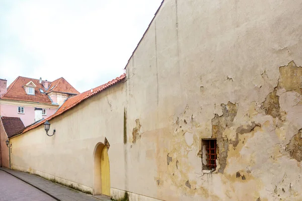 Street with a long wall of houses with street lights in the old center