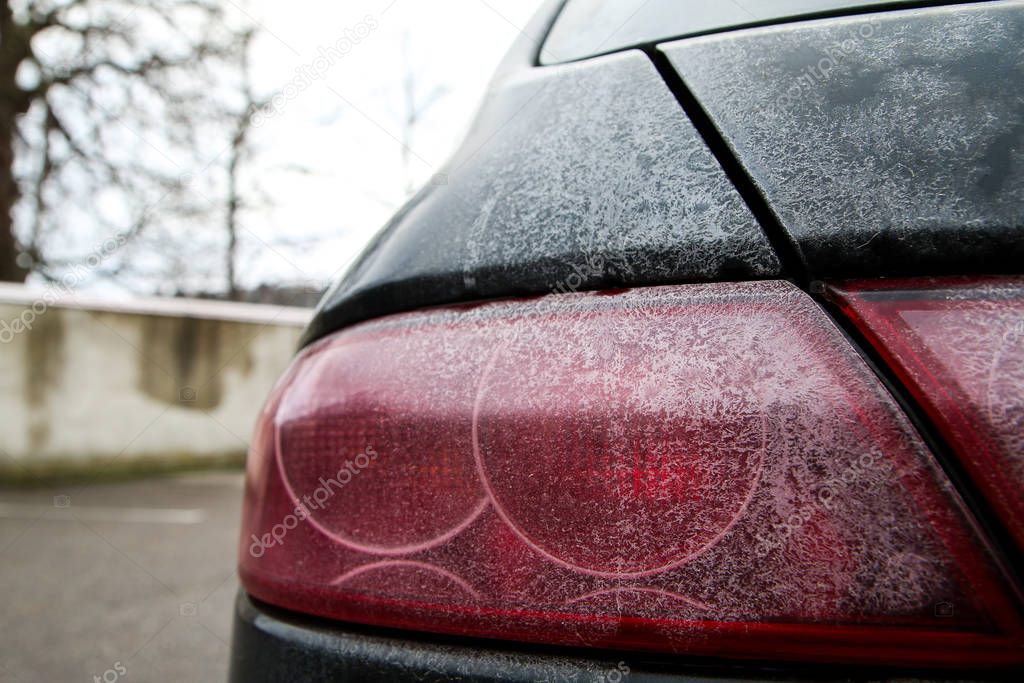 The detail of tail lights of a car during the winter season, dirty with maps from the salt or brine used against snow and ice on the roads.