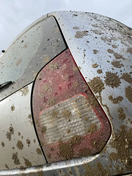 The detail of the car completely dirty by mud after the drag race on a field during winter. It needs complete cleaning of the exterior and interior.