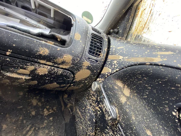 The detail of the car completely dirty by mud after the drag race on a field during winter. It needs complete cleaning of the exterior and interior.
