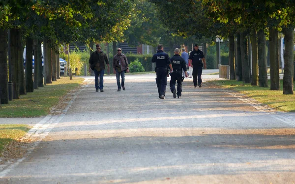 Oficiales de policía caminan junto a personas en zona de paseo parque — Foto de Stock