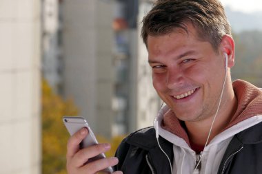 Smartphone balkonda güneşli gün boyunca kullanan adam