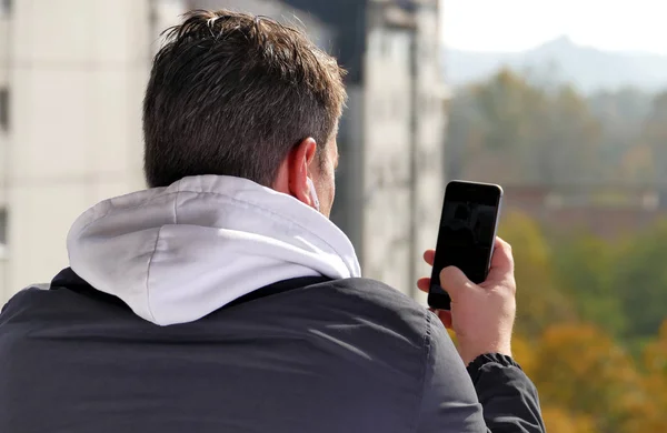 Uomo che utilizza smartphone sul balcone durante la giornata di sole Foto Stock