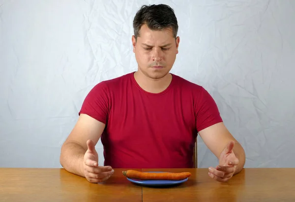 Jeune homme n'aime pas la carotte sur l'assiette, concept de nourriture saine . — Photo