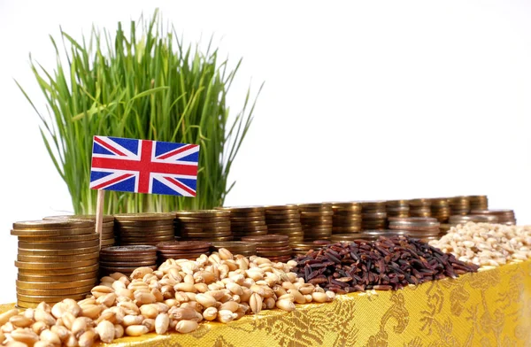 Bandeira da Grã-Bretanha acenando com pilha de moedas de dinheiro e pilhas de trigo — Fotografia de Stock