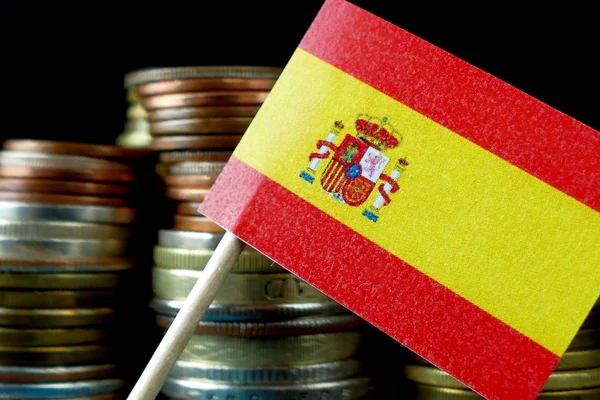 Spagna bandiera sventolando con pila di monete macro — Foto Stock