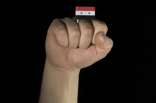Człowiek pięść rękę z flagę Syryjską na białym na czarnym tle — Zdjęcie stockowe
