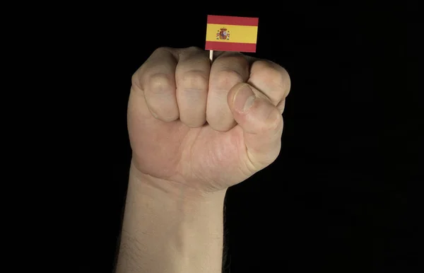 Puño de mano de hombre con bandera española aislada sobre fondo negro — Foto de Stock