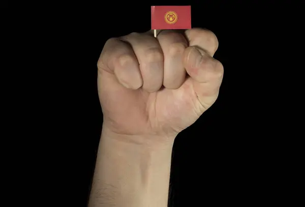 Man hand fist with Kyrgyzstan flag isolated on black background — Stock Photo, Image