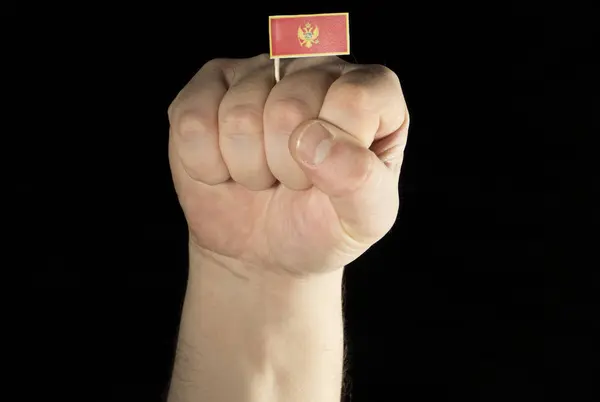 Кулак рука людина з прапор Чорногорії ізольовані на чорному фоні — стокове фото