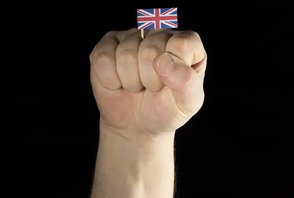 यूनाइटेड किंगडम ध्वज के साथ आदमी हाथ की मुट्ठी काले पृष्ठभूमि पर अलग — स्टॉक फ़ोटो, इमेज