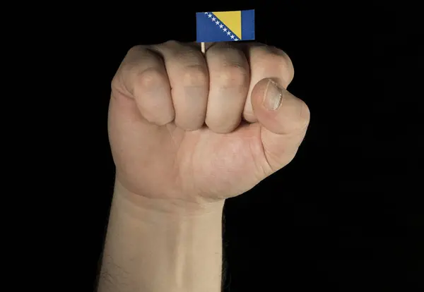 Ο άνθρωπος χέρι γροθιά με σημαία της Βοσνίας και Ερζεγοβίνης απομονώνονται σε μαύρο — Φωτογραφία Αρχείου