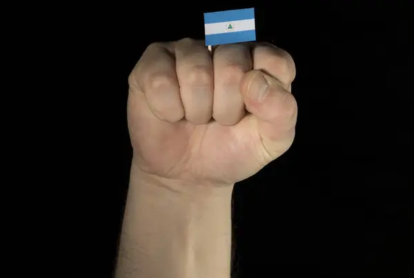 Рука человека с никарагуанским флагом на черном фоне — стоковое фото
