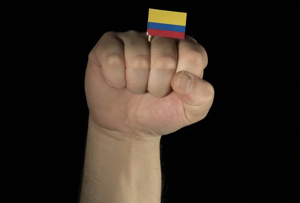 Man hand vuist met Colombiaanse vlag geïsoleerd op zwarte achtergrond — Stockfoto