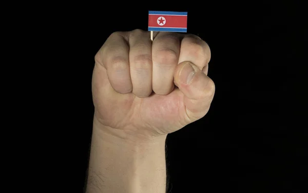 Puño de mano de hombre con bandera de Corea del Norte aislado sobre fondo negro — Foto de Stock